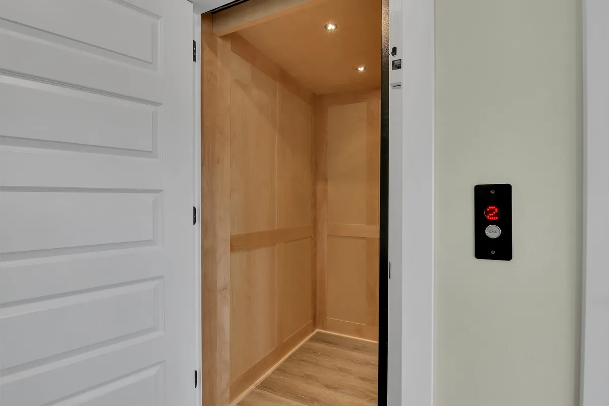 A modern and efficiently designed elevator interior with a visible control panel, offering seamless access between floors. The clean lines and neutral palette emphasize accessibility and contemporary convenience.
