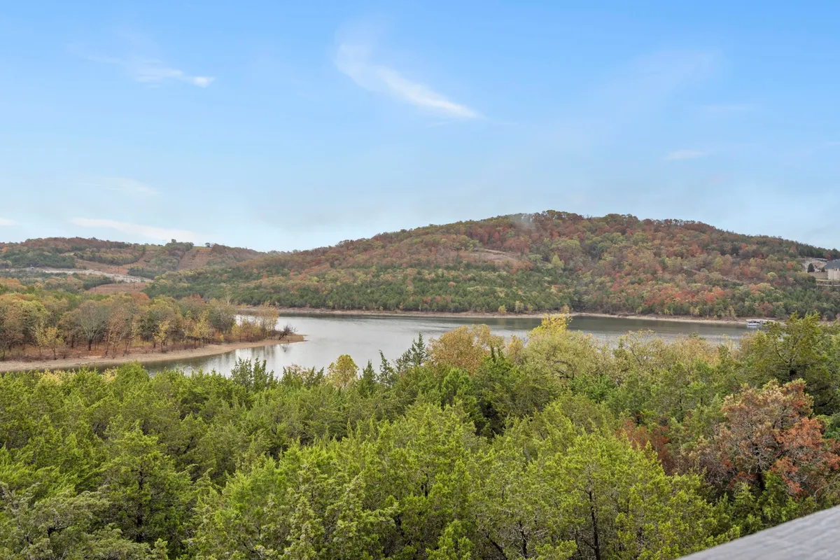 A serene vista of the lake with surrounding hills and vibrant autumn foliage, offering hints of nature trails and green spaces perfect for exploration. The tranquil water and expansive landscape encourage outdoor activity.