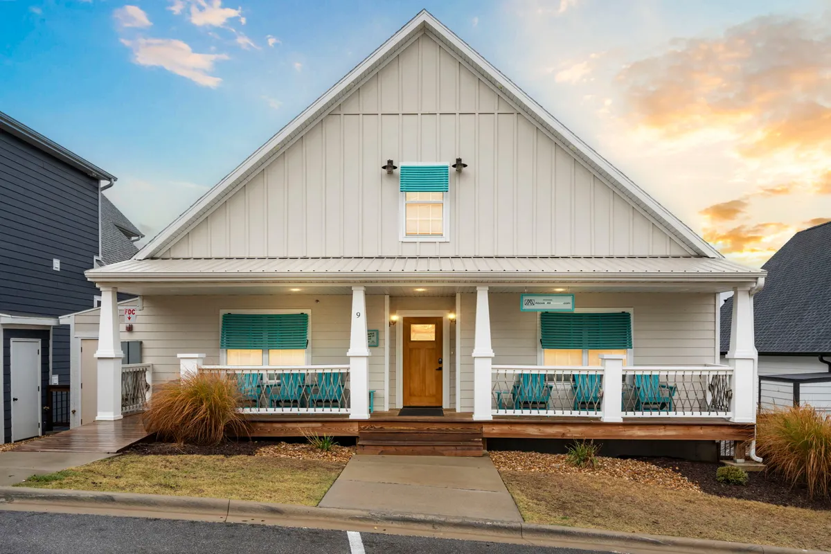 A welcoming exterior view of the home, featuring a front porch with decorative railing, shuttered windows, and landscaped surroundings. The porch presents easy access and offers a friendly spot for families to gather or relax.