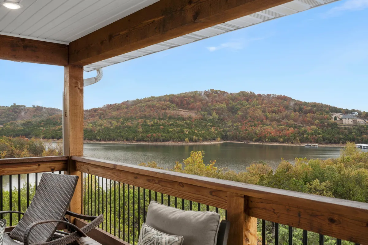 An inviting outdoor seating area on a wooden deck overlooks a scenic river with autumn foliage. Comfortable seating and a peaceful vibe make it an appealing spot for pet owners to relax after a walk.